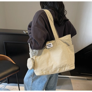 Detail of beige canvas tote bag with extra pockets and matching round coin purse pouch