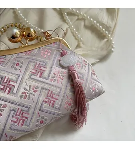 Detailed close-up of lavender silk embroidery with pearl clasp and long pink tassel
