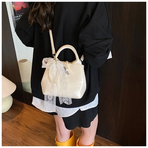 Detail of cream bucket bag featuring elegant lace trim and pearl accents on the surface