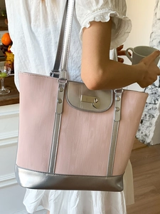 Sac fourre-tout rose et argent avec fermoir cœur porté par un mannequin dans un café