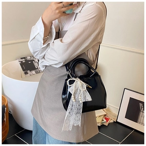 Black bucket bag featuring a decorative pearl lace bow and polished glossy finish