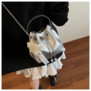 Détail du sac seau argenté avec nœud en dentelle perlée et cordon papillon chic