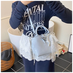 Detail of light blue bucket bag featuring a bamboo-style metal clasp and pearl bow decor
