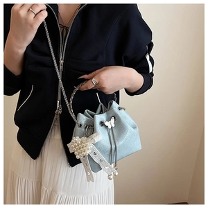 Détail du sac seau bleu clair avec poignée métallique argentée et nœud en dentelle