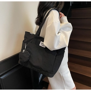 Detail of black canvas tote bag showing wash rules label and round zip coin pouch