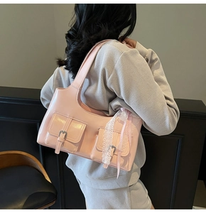 Dettaglio della borsa rosa lucida con pizzo e nastro sulla spalla della modella