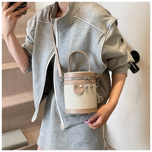 Borsa a secchiello beige intrecciata con finiture in pelle marrone indossata da modella