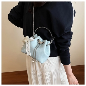 Détail du sac seau bleu clair avec poignée argentée, breloques perles et nœud dentelle