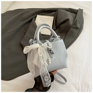 Detailed view of light blue bucket bag with pearl chain and lace bow decoration