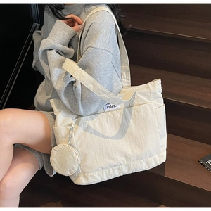 Close-up of cream canvas tote bag with side pockets and a round coin purse attachment