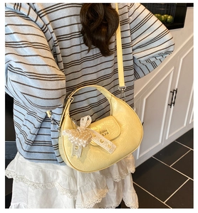 Détail du sac hobo jaune avec texture plissée, poignée en métal et nœud en perles