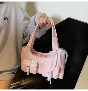 Dettaglio borsa rosa in pelle PU lucida con tasche anteriori e fiocco di pizzo decorativo
