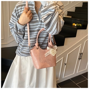 Detailansicht der rosa Ledertasche mit Faltenstruktur, Perlenanhängern und Metallringen