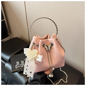 Vue détaillée du sac seau rose avec des rubans en dentelle et un pendentif cœur