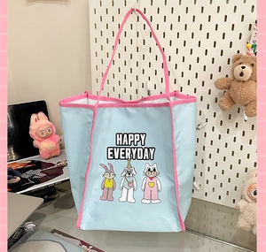 Close-up of cute cartoon embroidery and Happy Everyday text on blue tote bag