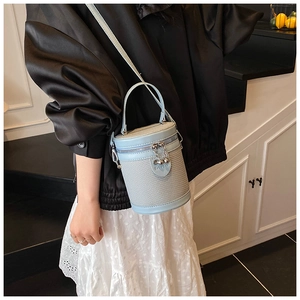 Dettaglio borsa a secchiello azzurra con trama intrecciata, finiture in pelle e zip a sfera