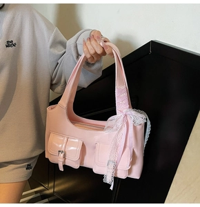 Dettaglio borsa sottospalla rosa lucida con tasche utility e fiocco in pizzo