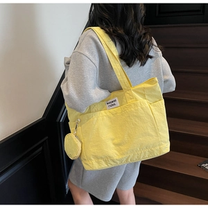 Detail of a large yellow canvas tote bag featuring multi-pocket design and a round coin purse