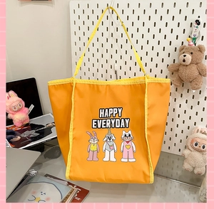 Detail of a large yellow nylon tote bag with cute animal cartoon print and text