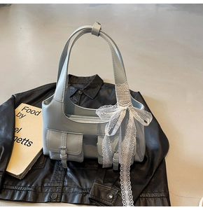 Dettaglio della borsa tote azzurra con fibbie metalliche e nastro decorativo in pizzo