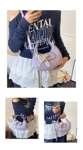 Détail du sac demi-lune lavande avec breloque cœur en perles et nœud en dentelle chic