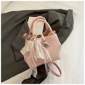 Close-up of pink bucket bag with large white lace bow and elegant pearl chain detail