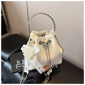 Détail du sac seau blanc cassé avec poignée argentée, nœud perlé et chaîne