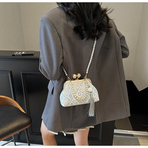 Detail of vintage jacquard handbag with pearl strap and elegant silk tassel detail