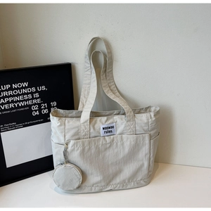 Detail of cream white nylon tote bag featuring external pockets and a small round coin purse