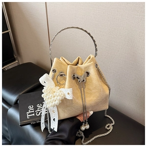 Détail du sac seau crème avec poignée métallique et breloque perle en cœur