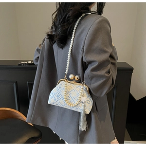 Close-up of blue embroidery pattern bag with pearl strap and elegant tassel detail