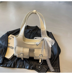 Dettaglio della borsa tote bianco crema con tasche a patta e fiocco su giacca di pelle