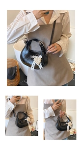 Détail du sac bandoulière noir en cuir huilé avec pendentif cœur et ruban soyeux