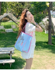 Close-up of sky blue tote bag with pink trim featuring cartoon embroidery in a park setting