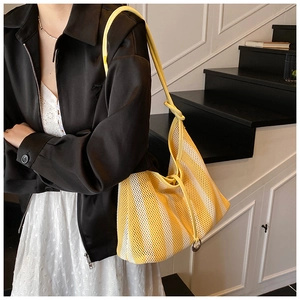 Détail d'un sac cabas en mesh rayé jaune et blanc avec lanière en cuir et anneau argenté