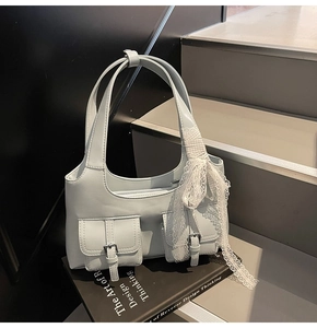 Dettaglio borsa tote azzurra con tasche anteriori e fiocco decorativo in pizzo