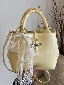 Cream yellow bucket bag with bamboo toggle closure and lace pearl bow detail