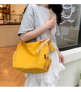 Détail du sac fourre-tout en nylon jaune avec poche zippée et cordon décoratif tressé