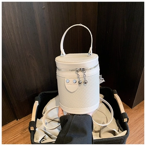 Dettaglio borsa a secchiello beige con trama intrecciata, doppia cerniera e toppa a cuore