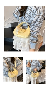Détail du sac croissant jaune clair avec breloque nœud en dentelle et logo en métal
