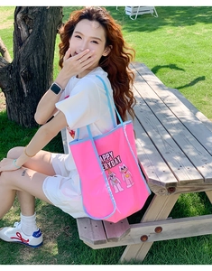Close-up of pink tote bag with blue trim and cute cartoon cat embroidery on grass