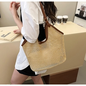 Detail of hand-woven beige straw tote bag with brown leather handles and metal hardware