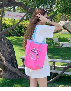 Detail of pink canvas tote bag featuring cute cartoon embroidery and blue shoulder straps