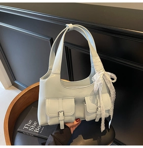 Dettaglio borsa tote in pelle azzurra con fiocco in pizzo e fibbie metalliche argentate