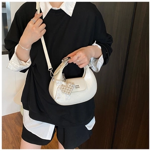 Détail du sac demi-lune crème avec texture plissée, breloque perle et nœud dentelle