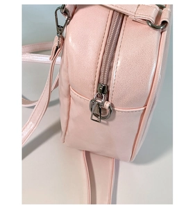 Vue détaillée de la texture du similicuir rose et de la fermeture éclair argentée du sac