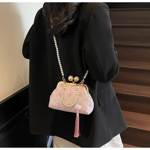 Detail of pink silk embroidery bag with pearl handle and silk tassel on wooden stairs