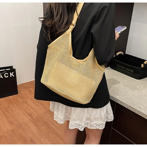 Close-up of minimalist beige woven hobo bag with breathable mesh texture and wide shoulder strap