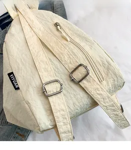 Détails des bretelles réglables et des boucles en métal sur un sac à dos blanc cassé