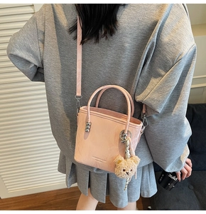 Detail of pink bucket bag with a cute plush bear charm and detachable shoulder strap